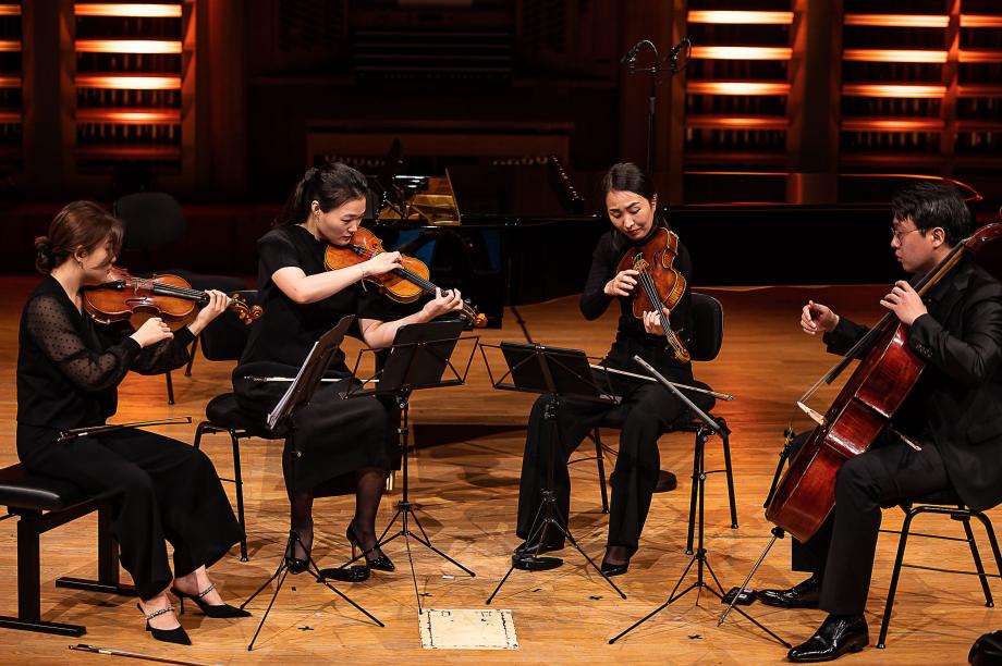 Musizierendes Streichquartett auf dem Podium des Konzertsaales.