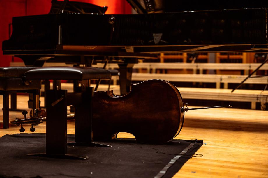 Vor dem Steinway-Konzertflügel liegt auf der Seite positioniert Violoncello.