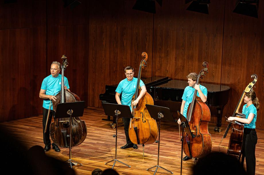 Kontrabassquartett unter der Leitung von Prof. Matthias Weber im Kammermusiksaal. Alle tragen das türkisfarbene HMDK-Shirt.