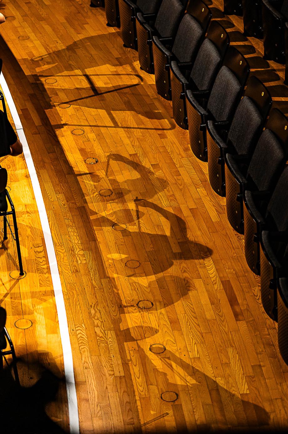 Die Schatten musizierender Studierenden zeichenen sich auf dem hellen Parkett der Vorbühne ab.