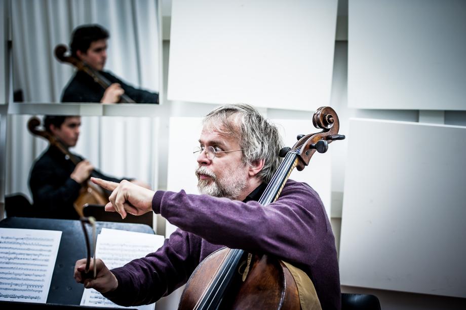 Violoncelloprofessor Conradin Brotbek beim Unterricht. Er fordert mit seinem Blick die volle Aufmerksamkeit des Gegenübers ein. Im Hintergrund ist der Studierende in einem der Spiegelpanele zu sehen.
