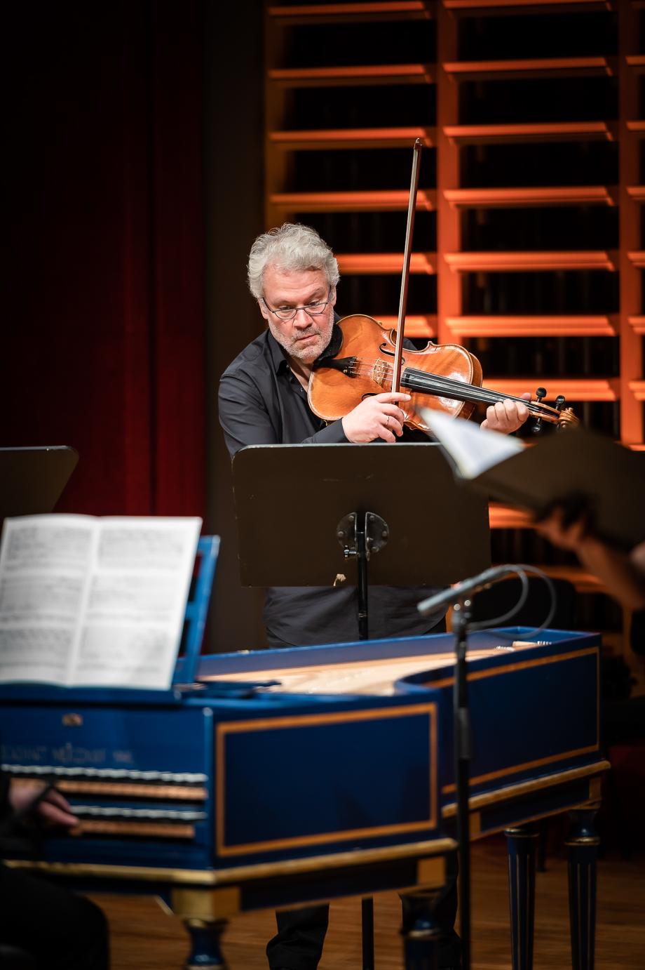 Violaprofessor Stefan Fehlandt musizierend auf dem Podium. Im Vordergrund steht ein blaufarbenes Cembalo.