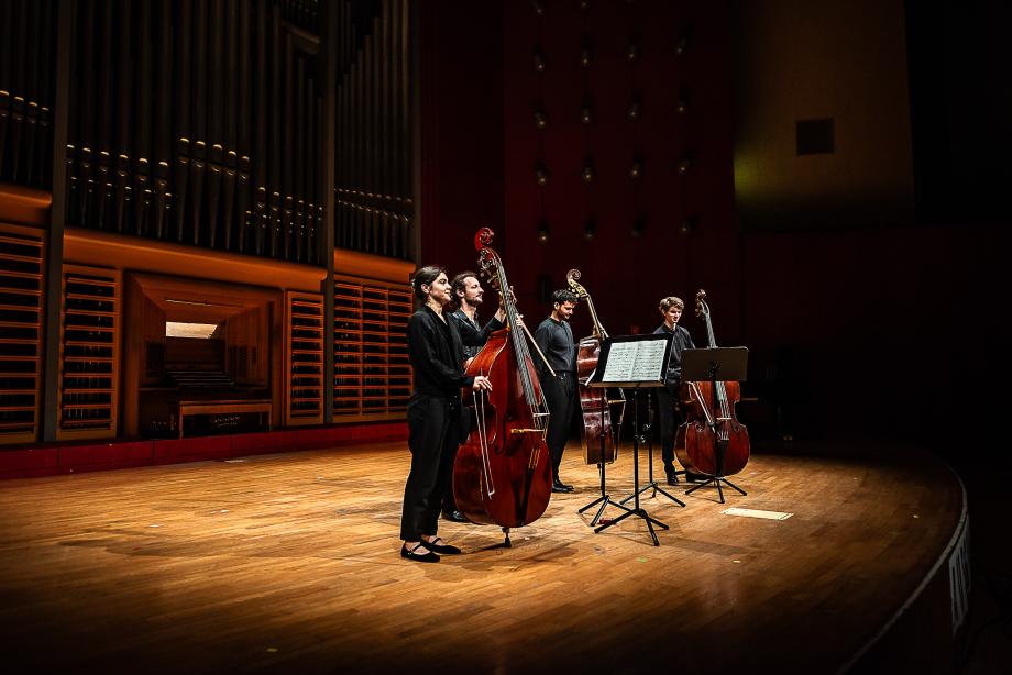 Kontrabassquartett beim Schlussapplaus auf dem Konzertsaalpodium. 