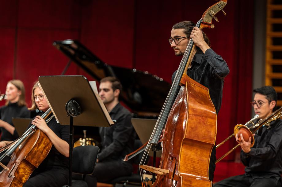 Student der Kontrabassklasse steht im Mittelpunkt. Darum gruppieren sich einzelne Studierende.