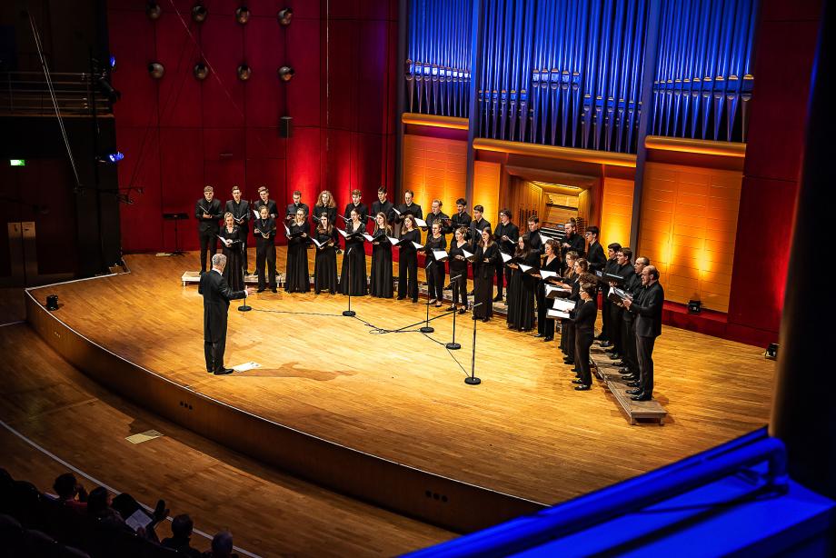 Portraitaufnahem von Prof. Denis Rouger und dem Kammerchor der HMDK Stuttgart.