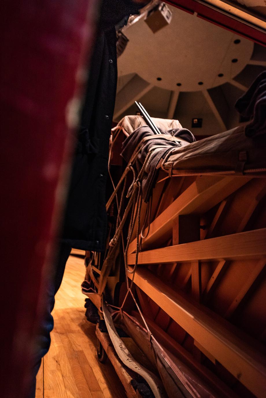 Der neue Konzertflügel steht noch hochkant und verpackt auf dem Holzwagen im Konzertsaal.