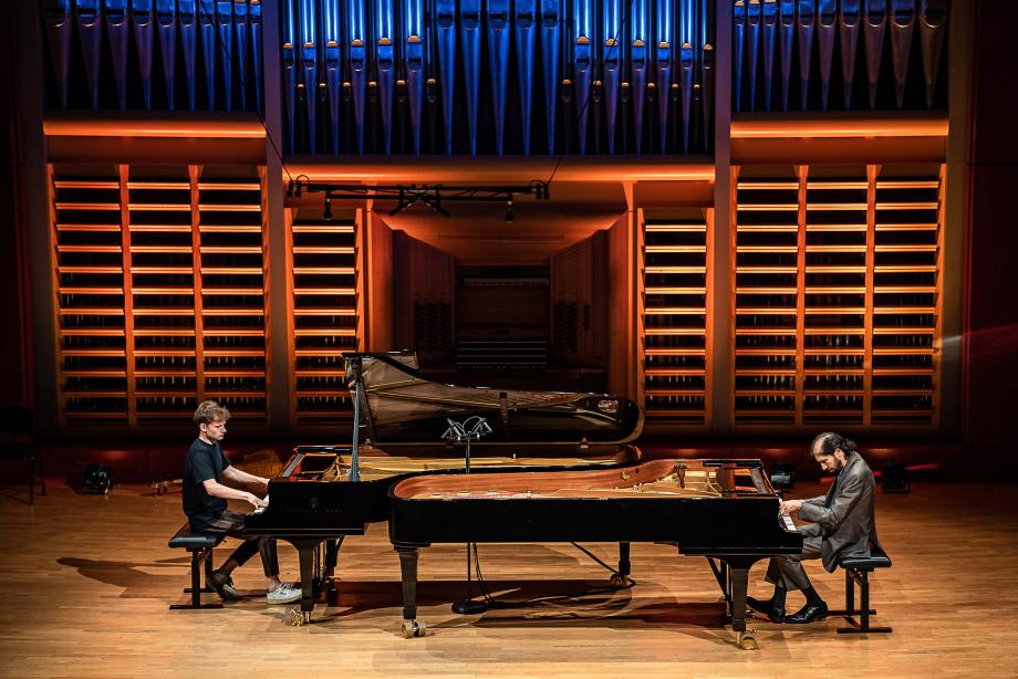 Klavierprofessor Noam Sivan konzertiert mit einem Studierenden aus seiner Klasse an den beiden Konzertflügeln im Konzertsaal.