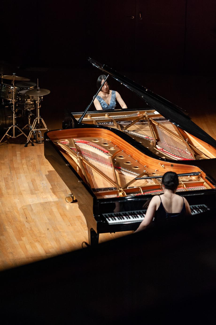 Aus der Vorgelperspektive sind beide Konzertflügel, zwei Pinaistinnen und ein Schlagzeugaufbau im Hintegrund zu sehen.