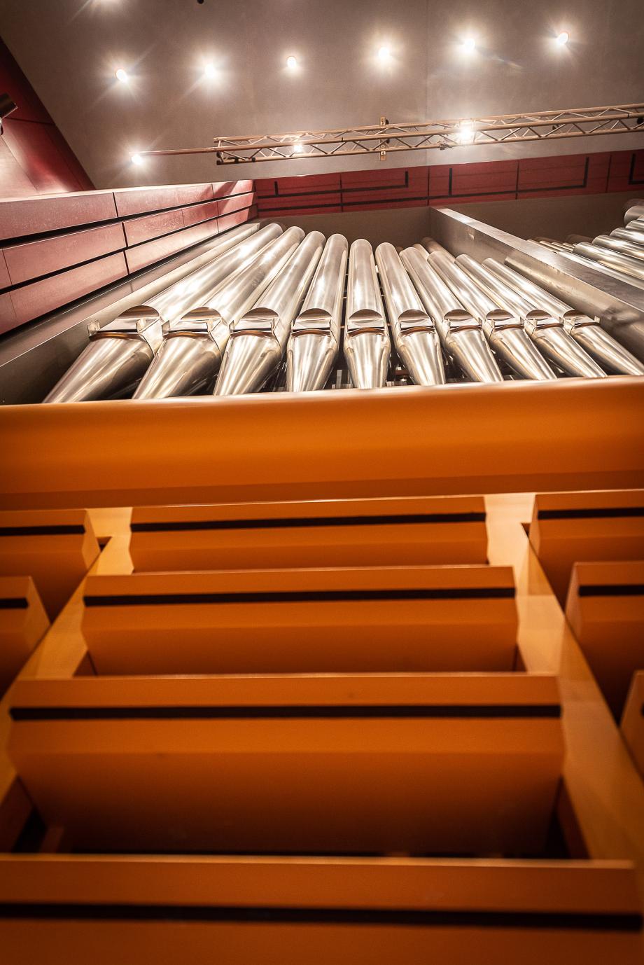 Blick von unten auf die aufgeklappten Orgelschweller und das silberfarbene Orgelprospekt.
