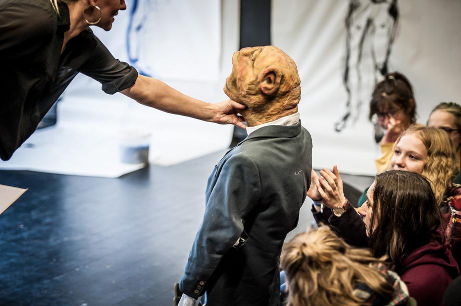 Eine in Anzug gekleidete Handpuppe wird Interessierten gereicht.