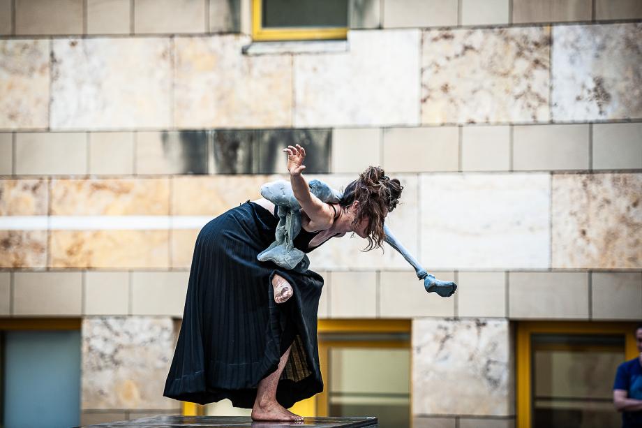 Studierende des Figurentheaters balanciert einbeinig auf einem Steinquader nur den Beinbereich einer Puppe.