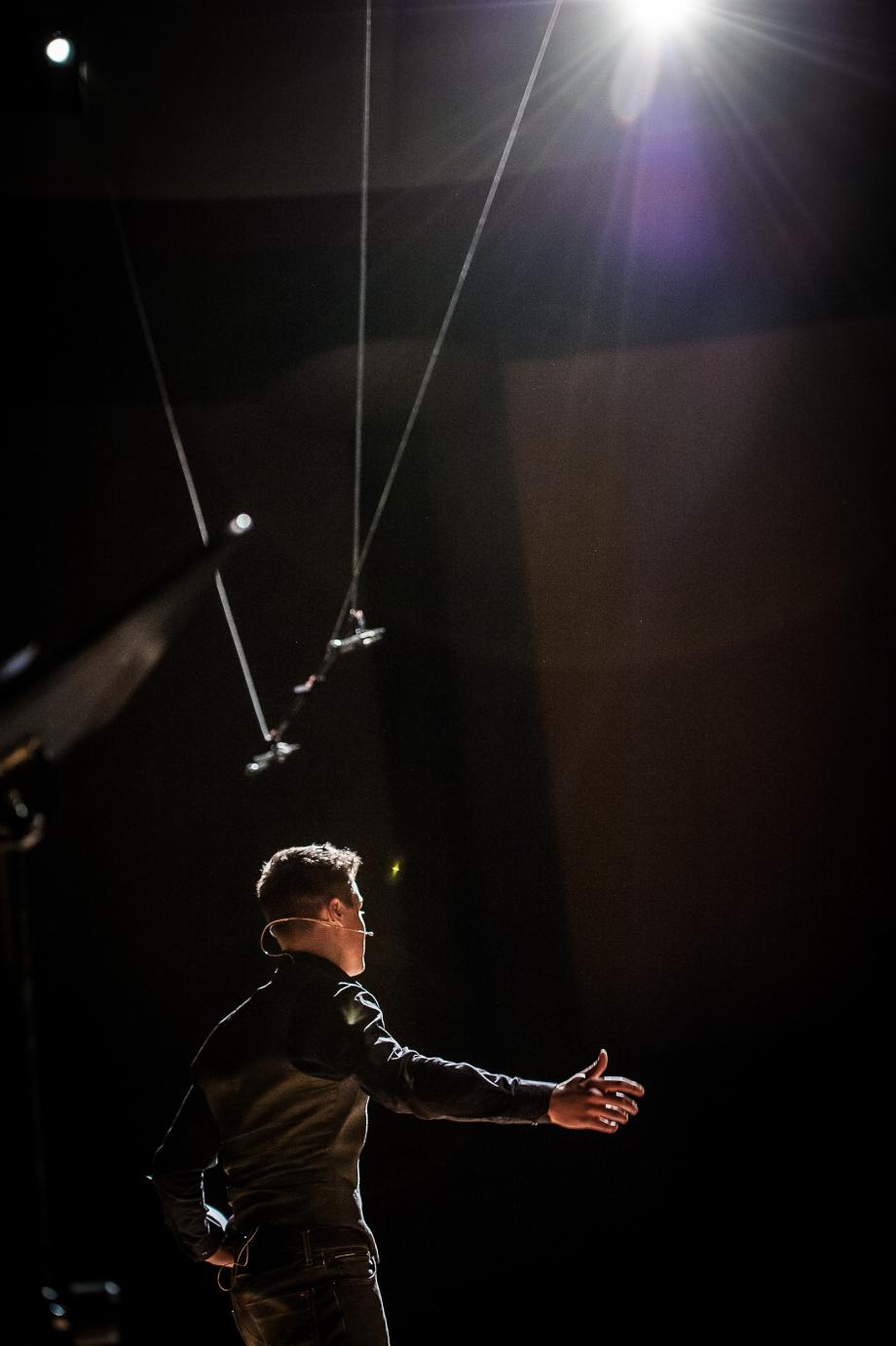 Student der Sprechkunst von hinten beobachtet, der seinen rechten Arm ausgebreitet und den Blick auf den Zuschauerraum ausgerichtet hat.