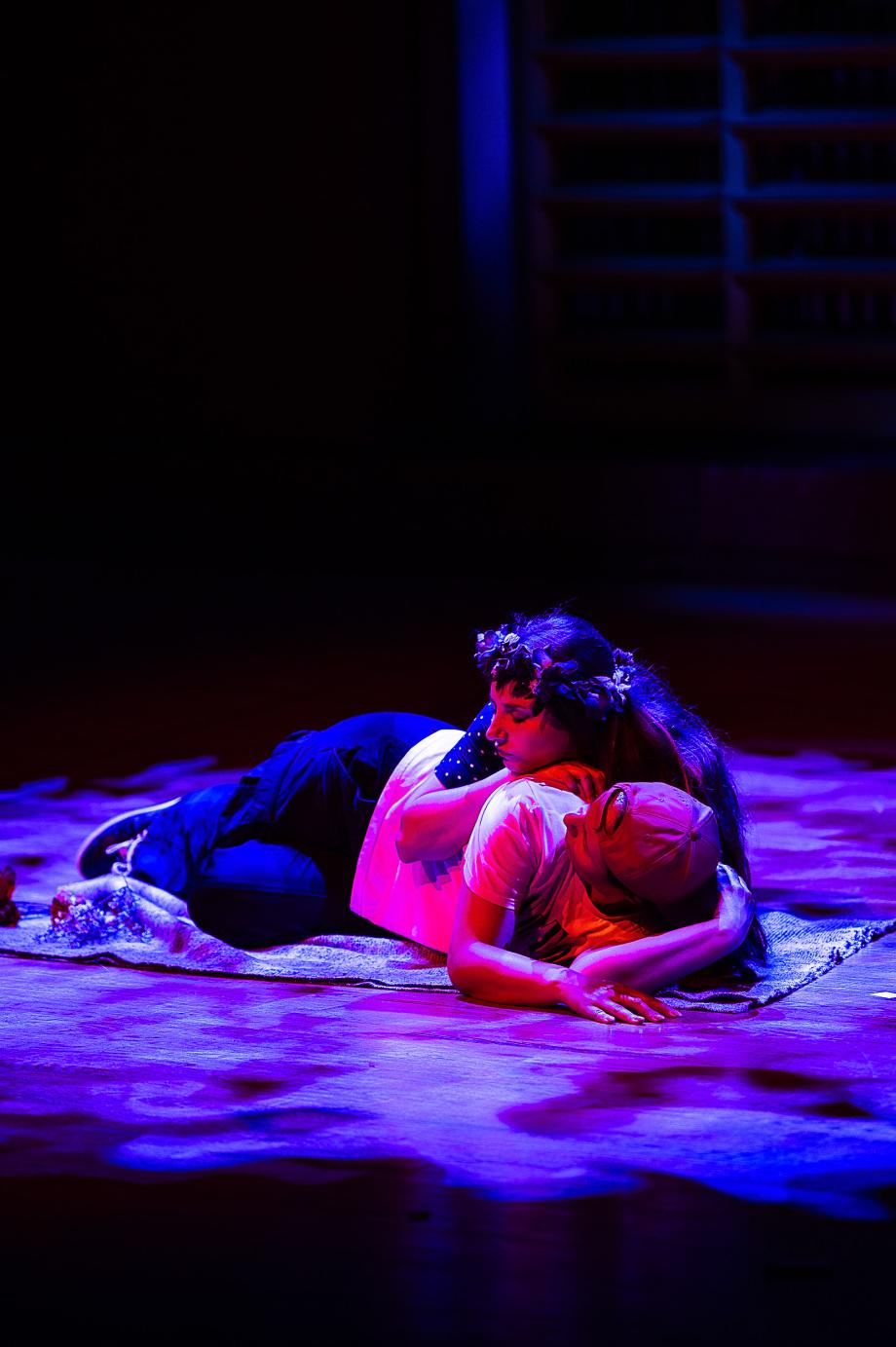 Studierende liegen auf einer Decke und umarmen sich.