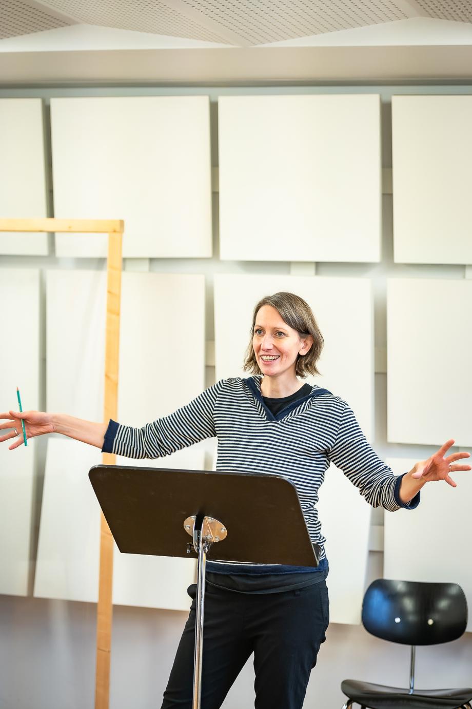 Dozentin Katja SChumann hat ihre beiden Arme ausbreitet und erklärt ihrem Publikum eine Situation.