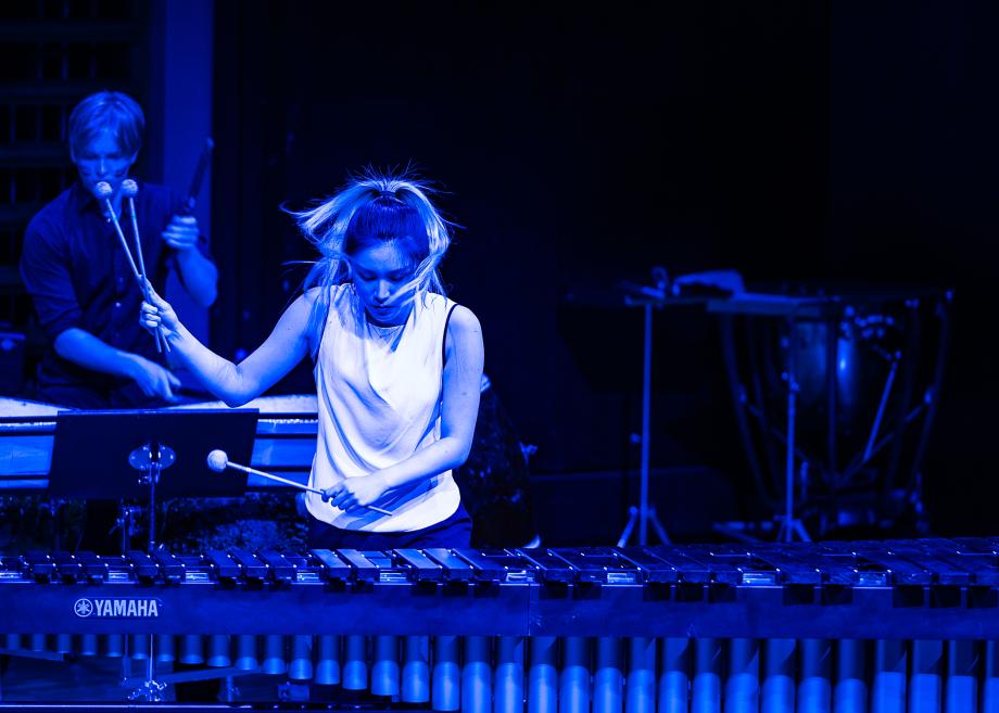 Studentin spielt Vibraphone in blauem Licht.