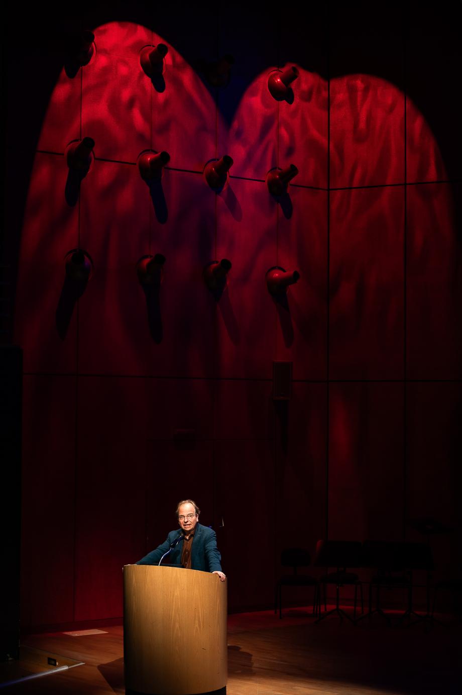 Prof. Dr. Andreas Meyer im Konzertsaal der HMDK. Im Hintergrund ist die Wand atmosphärisch rötlich marmoriert.