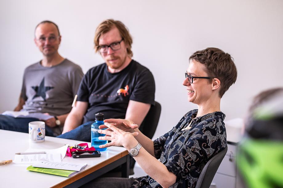 Prof.in Britta Wirthmüller gestikulierend im Gespräch mit Studierenden und Lehrenden.