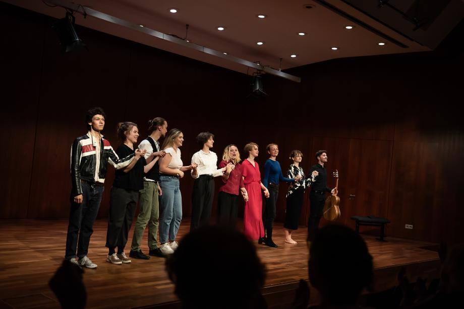 Menschen auf Bühne: Verbeugen sich udn halten sich an den Händen