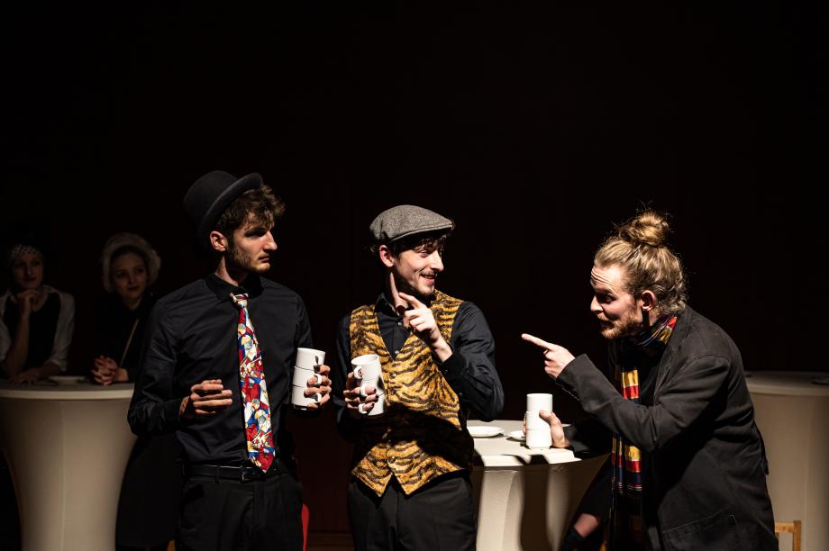 Drei Männer kommunizieren miteinander während sie je drei Tassen halten.