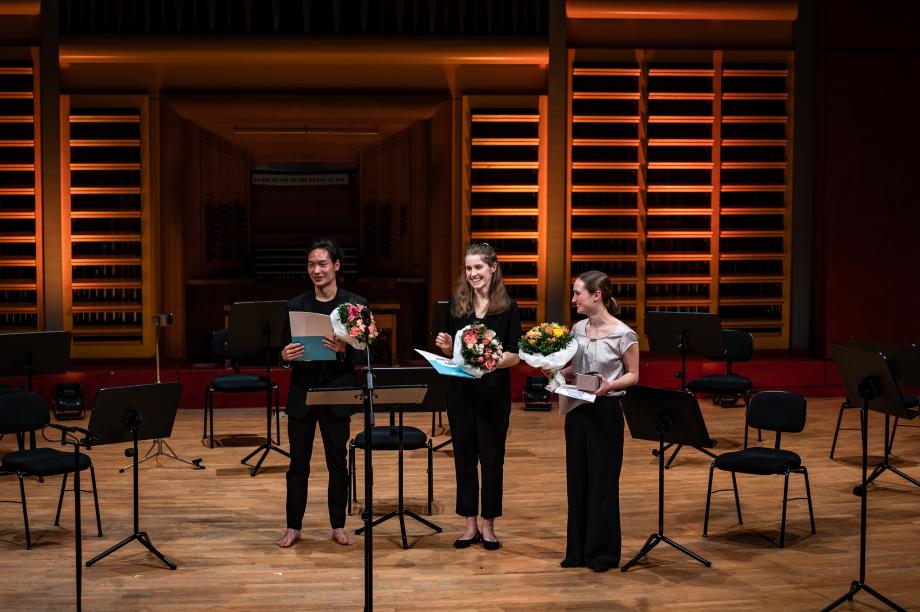 Drei Preisträger und Preisträgerinnen mit Blumensträußen beim Domnick Cello Wettbewerb 2022