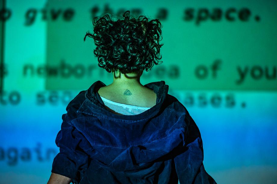 Frau schaut auf Leinwand mit Text. Sie hat dem Betrachter den Rücken zugekehrt.