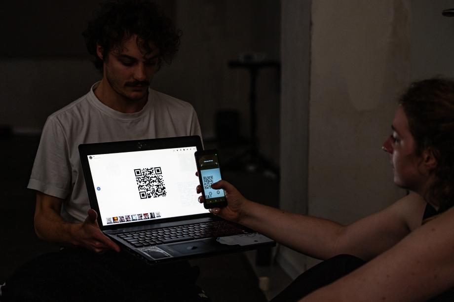 Frau scannt mit einem Handy einen QR-Code von einem Laptop ab.