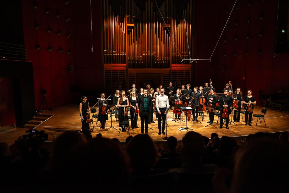 Studioorchester vor der beleuchteten Orgel im Konzertsaal.