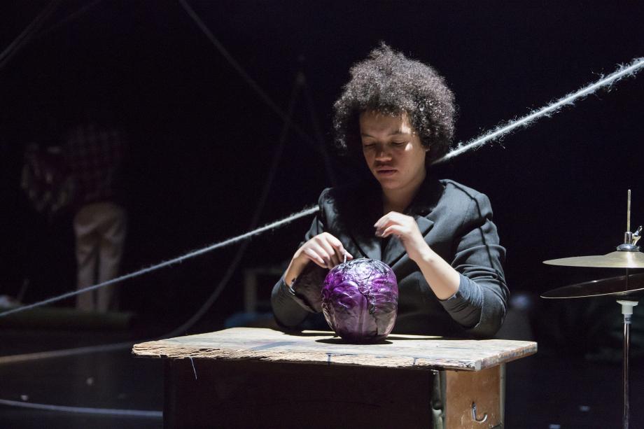 Frau sitzt an einem kaputten kleinen Holztisch und schaut auf den vor ihr liegenden Rotkohl.