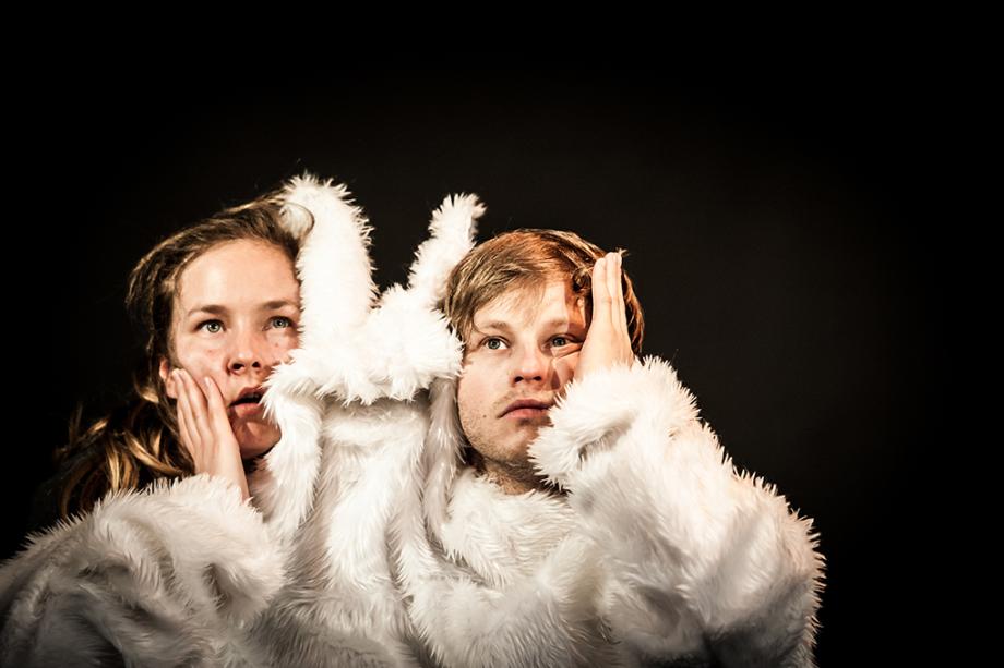 eine Frau und ein Mann tragen ein gemeinsames weißes Hasenfellkostüm, mit einer freien Hand zerknautschen sie sich selbst ihr Gesicht.