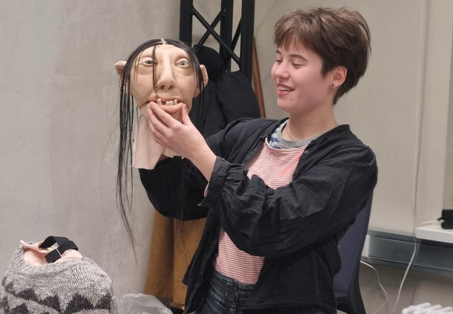 Studentin hält Figurenkopf in ihrer Hand und lacht.