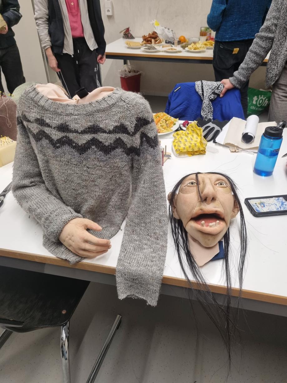 Figurenkopf und Torso stehen getrennt voneinander auf dem Werkstatttisch.