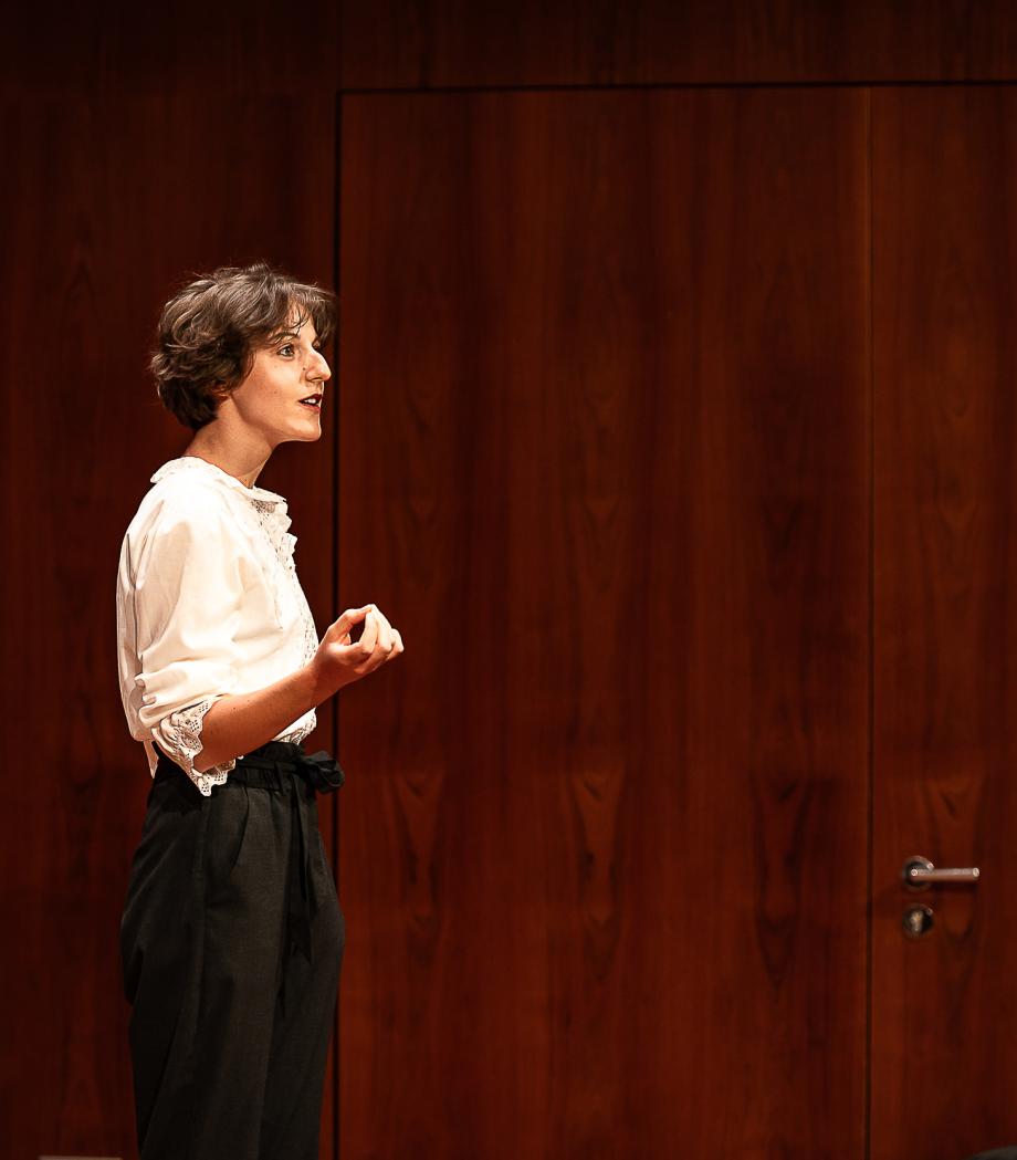 Frau spricht auf Bühne.