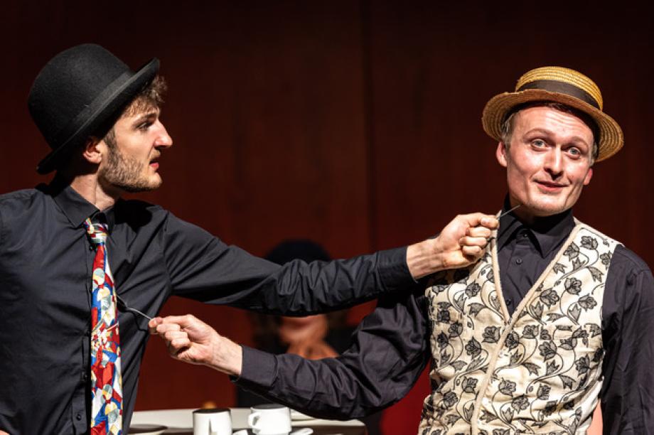 Zwei Männer mit Hüten bedrohen sich gegenseitig mit Löffeln.