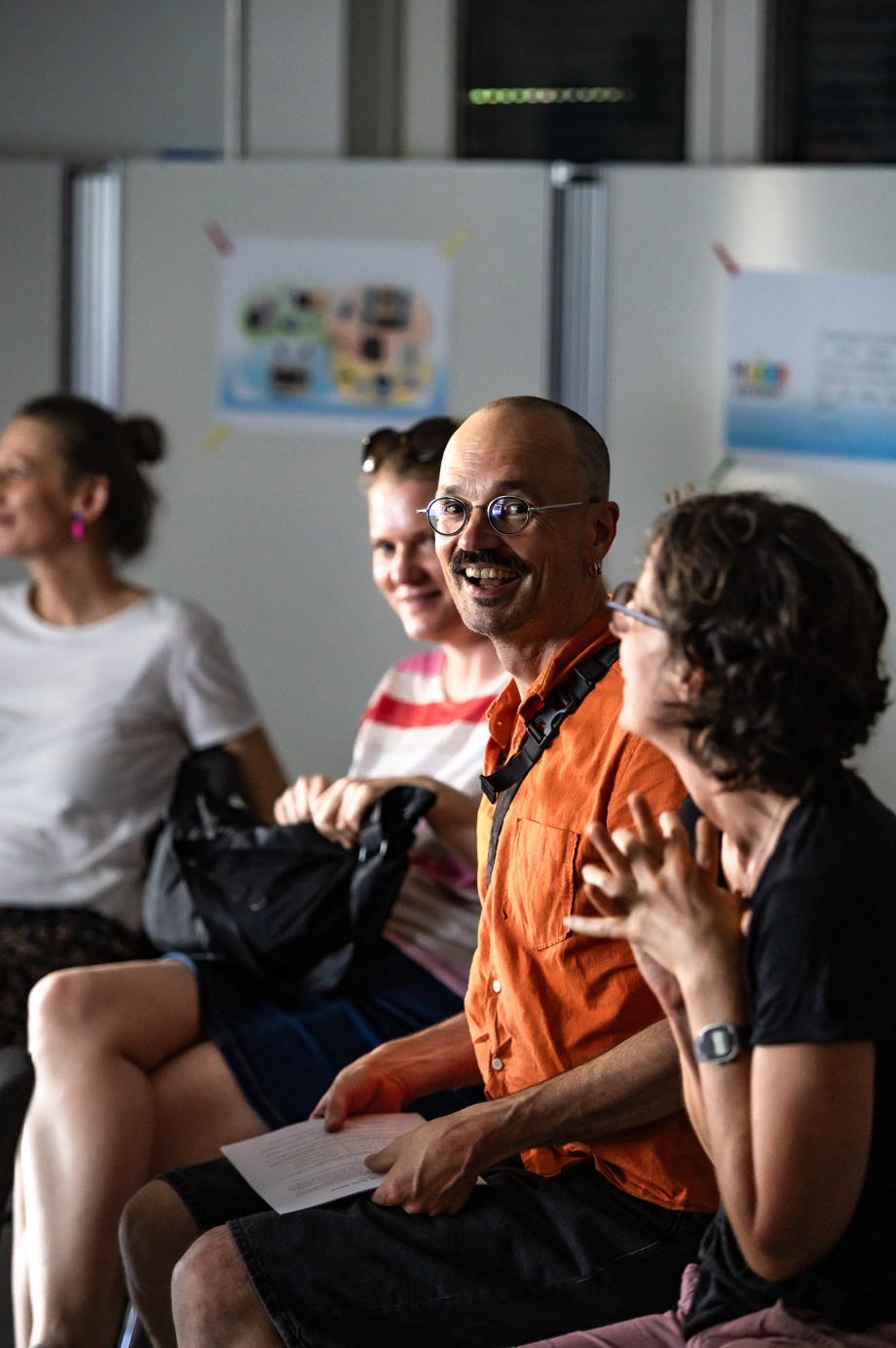 Prof. Christian Grüny sitzt im Publikum und strahlt in die Kamera.