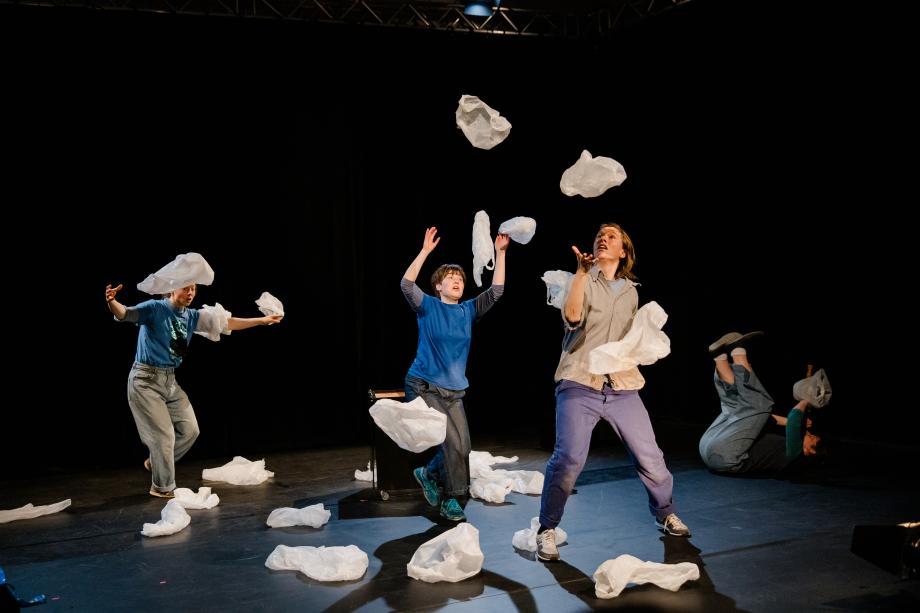 Vier Frauen schmeißen Kunststofftüten, die an Wolken erinnern, in die Luft.