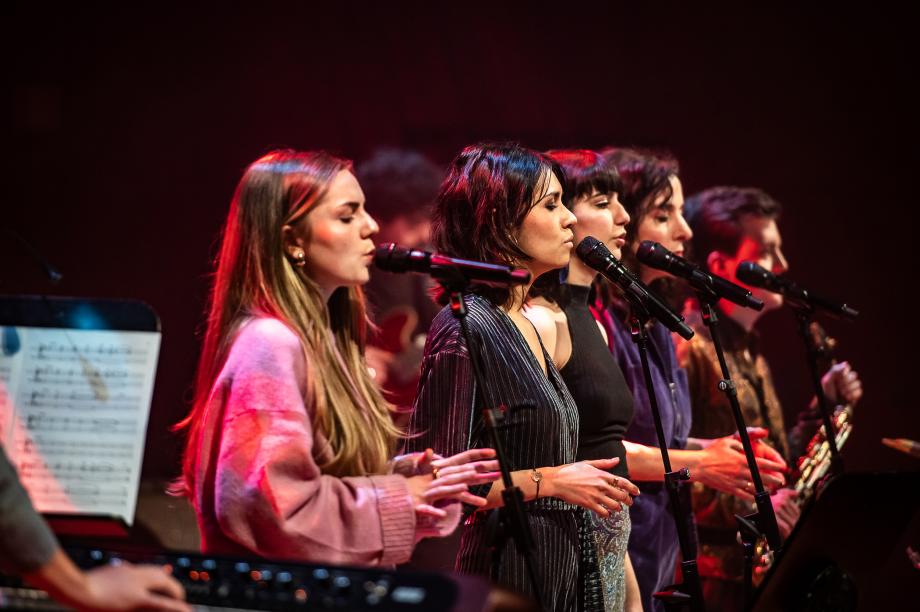 Vier Jazzsängerinnen stehen an Mikrofonen und singen gemeinsam mit geschlossenen Augen.