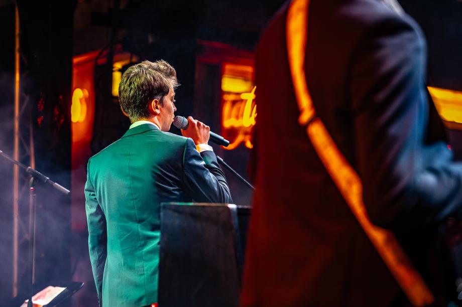 Ein Sänger steht am Mikrofon auf der Freiluftbühne. Die Bühne ist in Nebel getaucht.