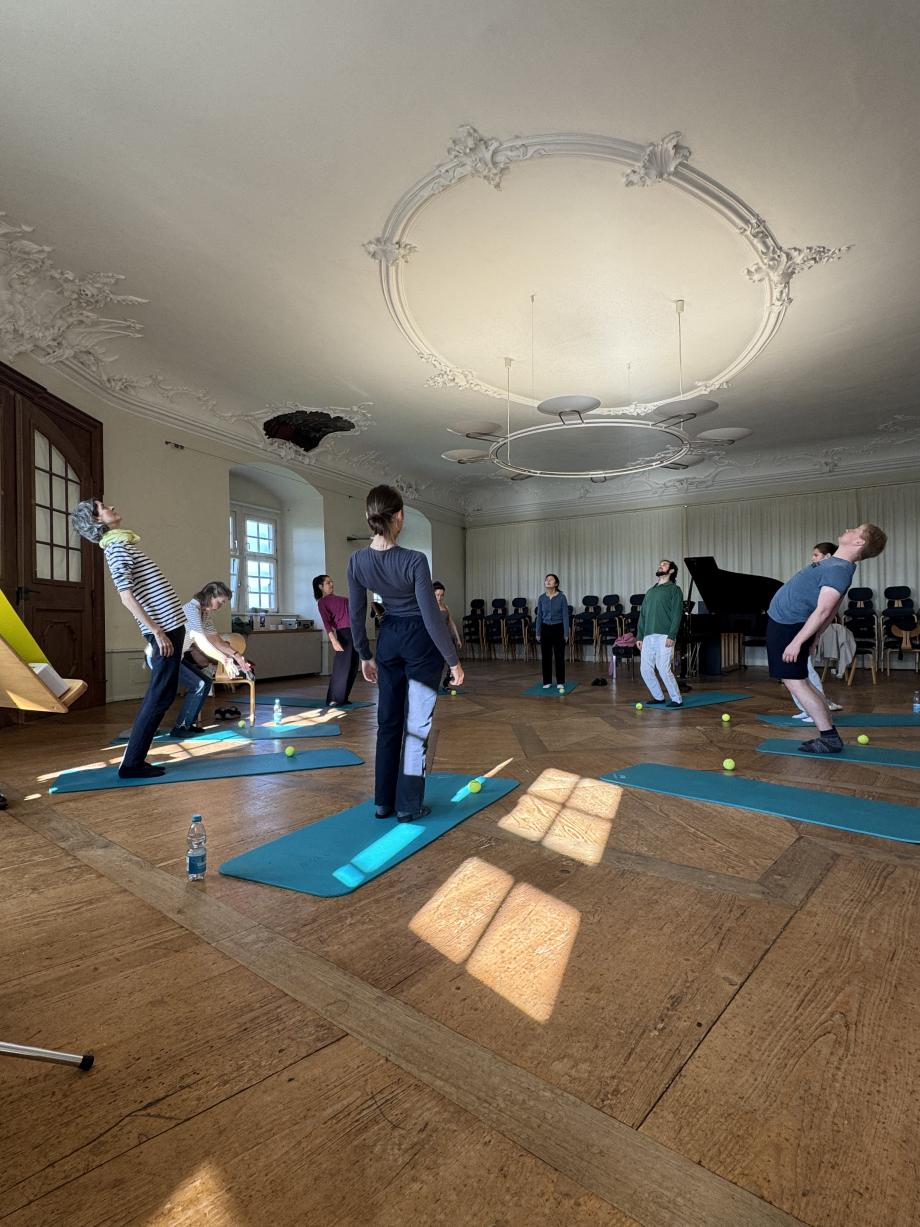 Studierende bei Körperübungen in einem historischen Saal auf Schloss Kapfenburg.