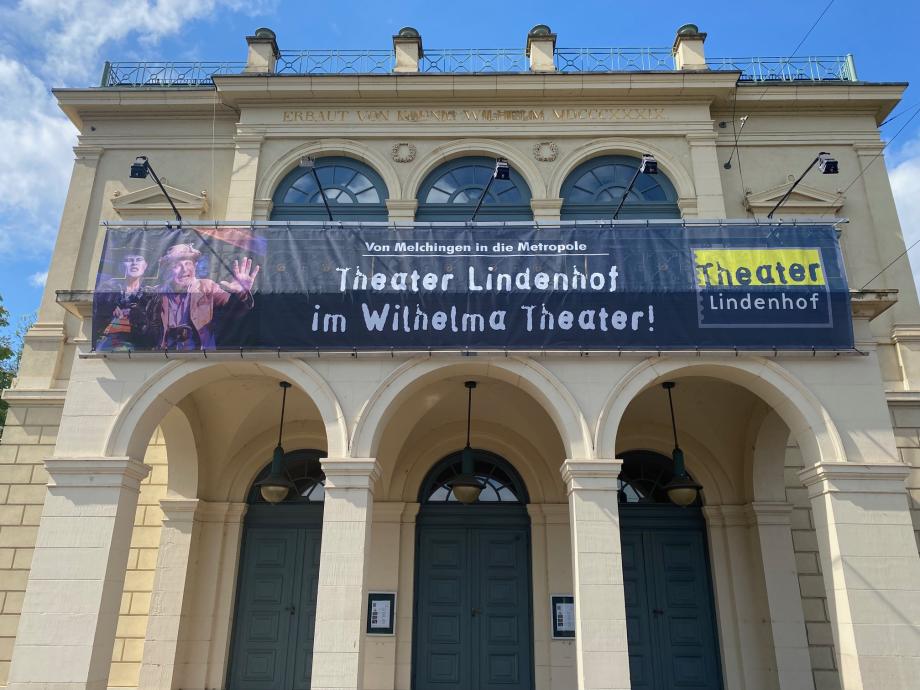 Banner des Theater Lindenhof vor der Fassade des Wilhelma Theaters