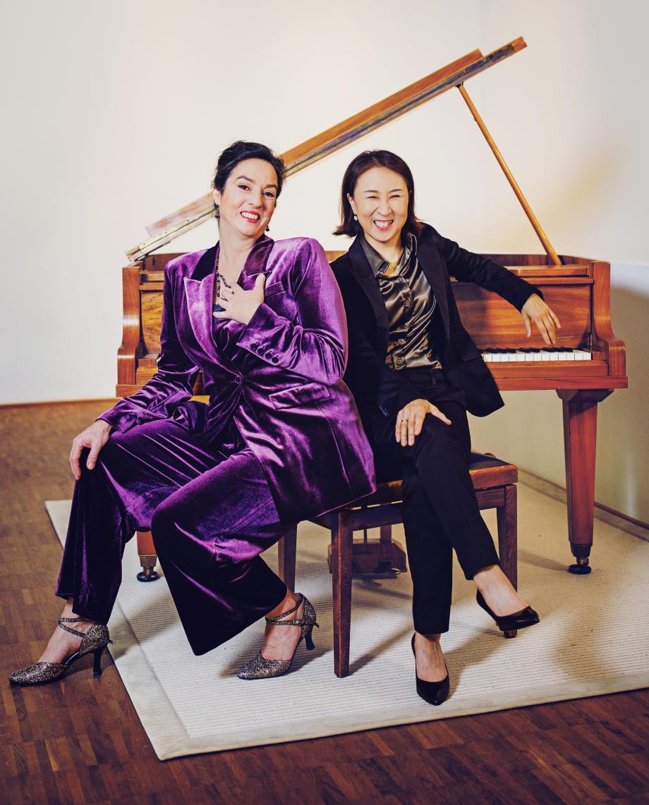 Franziska Dannheim und Jeong-Min Kim sitzen in schicken Anzügen vor einem brauchen Flügel