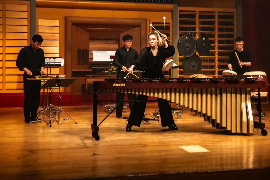Es sind vier Percussion-Studenten musizierend auf der Bühne zu sehen. Im Mittelfokus steht SeongYeon Kong und spielt Marimbaphon. Hinter ihr spielen David Dong, Meng-Fu Hsieh, und Xia Yuan weitere Schlaginstrumente.