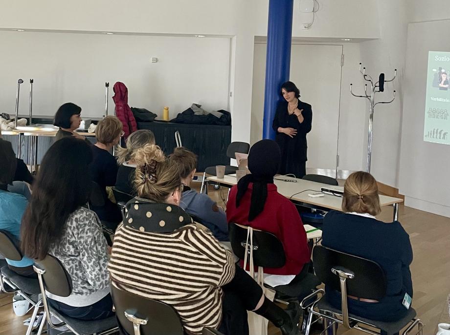 Die Referentin spricht zu ihrem Publikum, welches von hinten zu sehen ist.