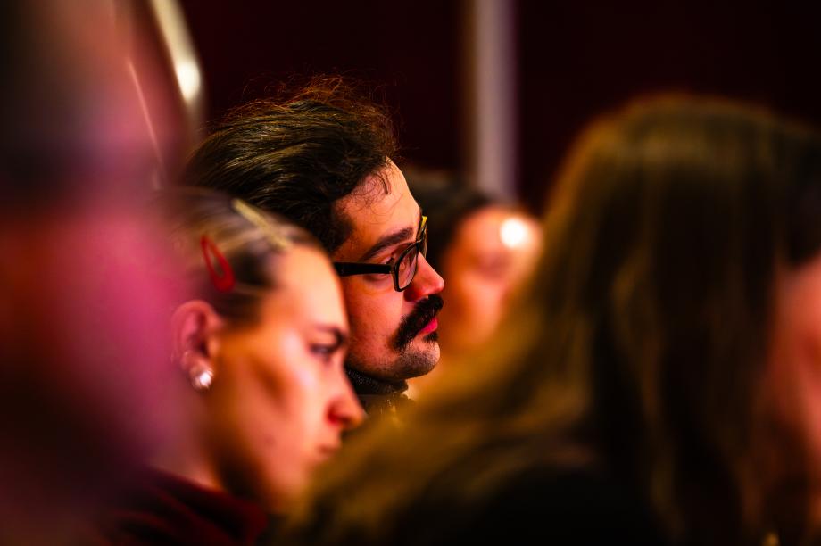 Studierende während der Eröffnung im Publikum des Konzertsaals. Sie schauen interessiert zur Bühne.