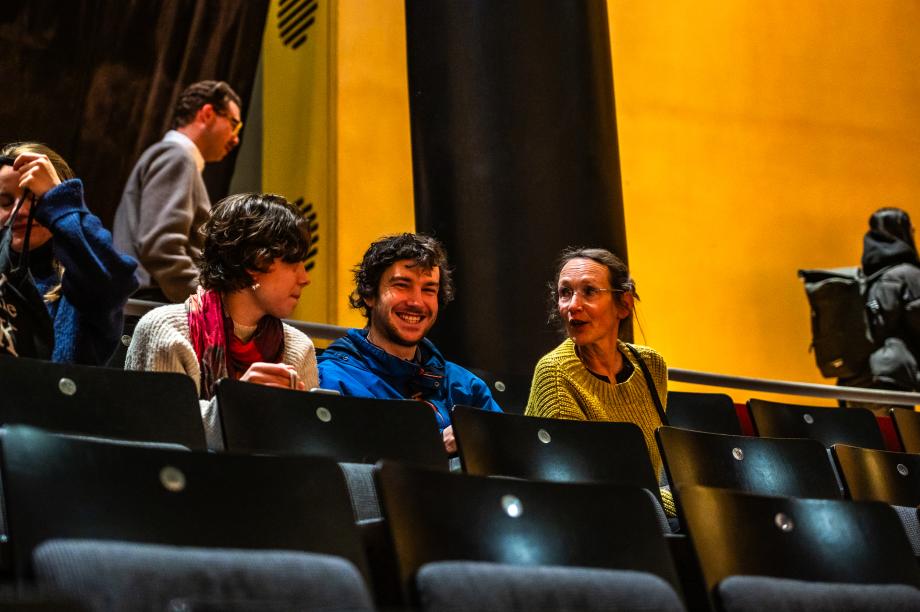 Studierende und Lehrende vor Beginn der Eröffnung im Publikum des Konzertsaals. Sie unterhalten sich angeregt.
