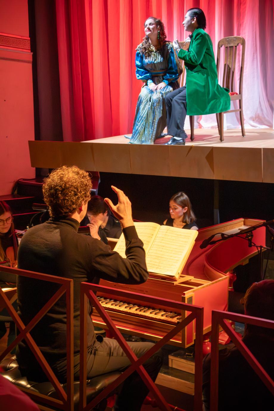 Jörg Halubek dirigiert die Produktion "Poppea", eine Solistin ist auf der Bühne zu sehen.