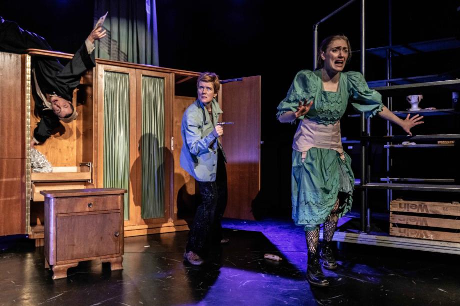 Spielszene mit drei Spieler*innen vor einem Schrank