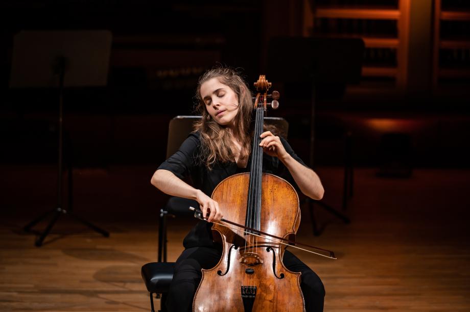 Preisträgerin des Cellowettbewerbs 2022 spielt beim Preisträgerkonzert auf der Bühne des Konzertsaals. Er hat die Augen geschlossen und spielt mit sichtbarere Leidenschaft.