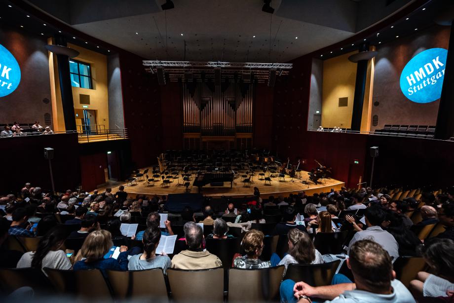 Der mit Publikum gefüllte Konzertsaal. Der Raum ist abgedunkelt kurz vor dem Konzertbeginn.