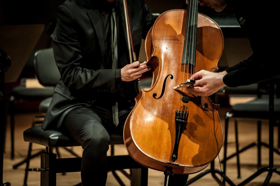 Ein Violoncello wird mit einem Mikrophon auf dem Steg präpariert.