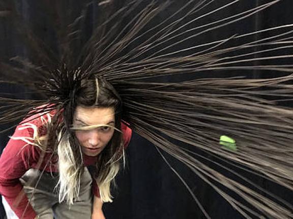 Frau schleudert ihre Haare, die aus Weidenruten sind herum.